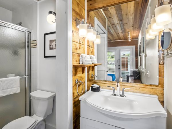 A modern bathroom features a shower, toilet, vanity with a sink, and wooden accents, illuminated by stylish light fixtures.